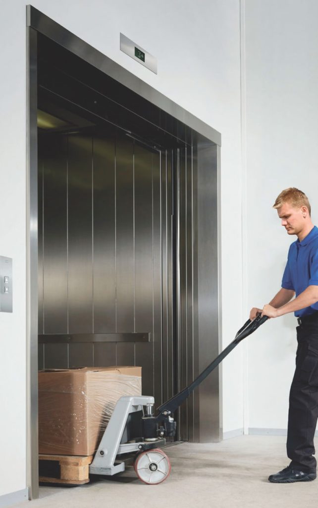Worker loading goods into a large freight lift